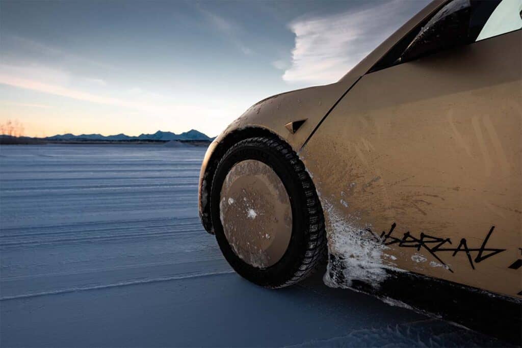 Coche eléctrico en un paisaje nevado con montañas al fondo, preparado para atravesar superficies heladas.